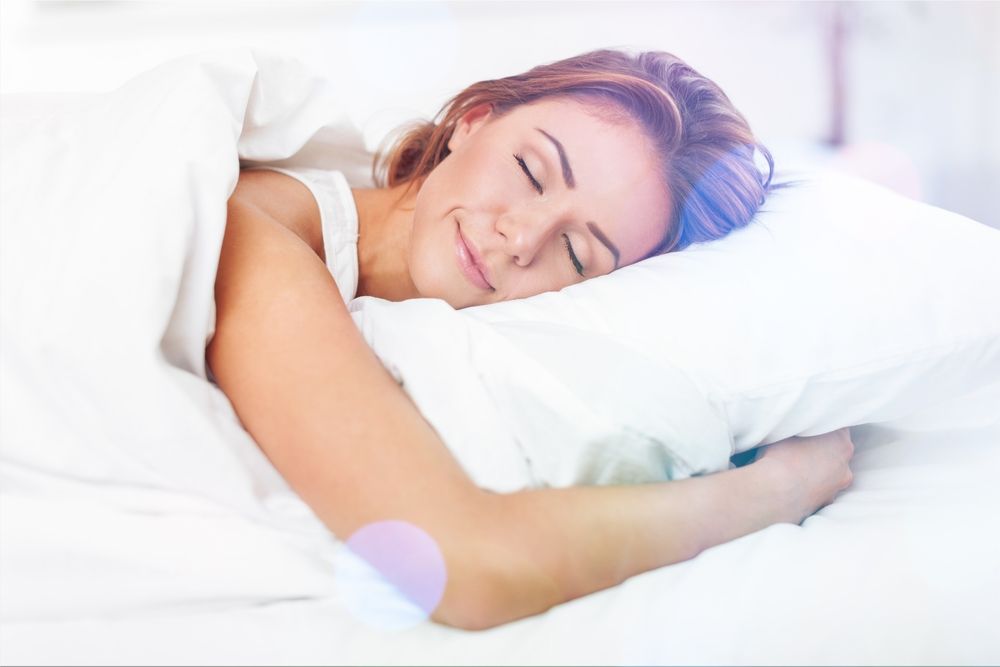 mujer durmiendo sobre una cama con sabanas blancas