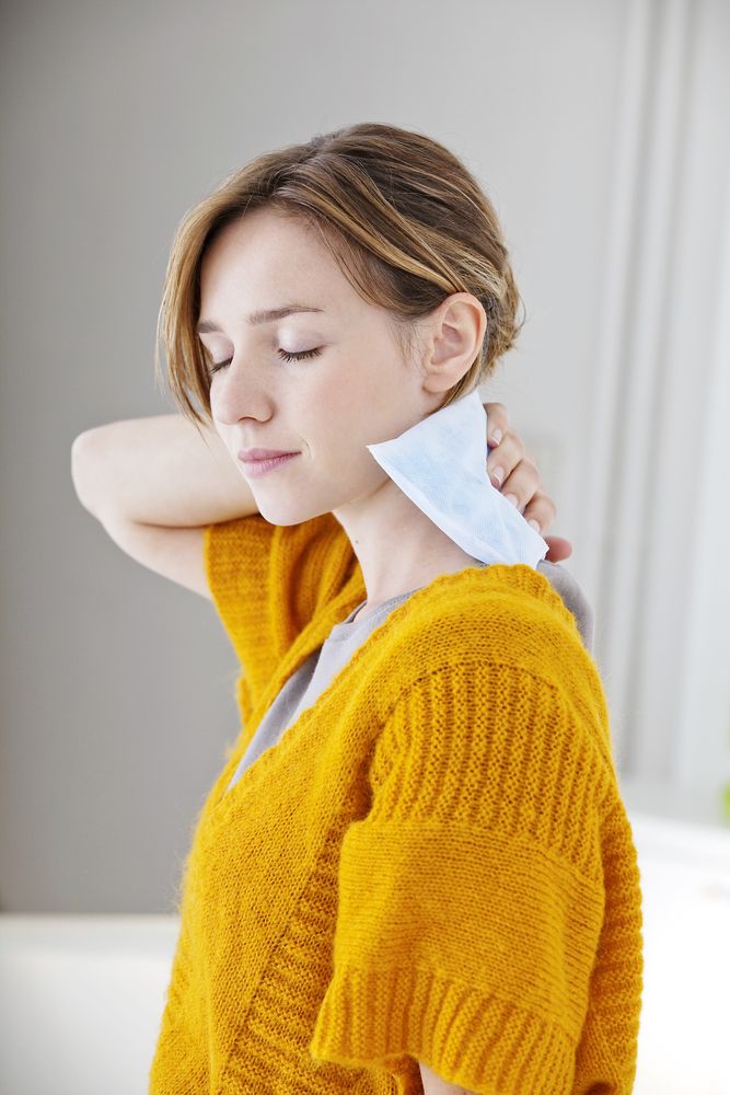 mujer aplicando una compresa caliente sobre su cuello