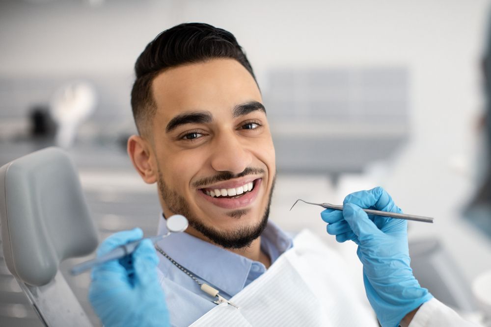 Hombre sonriente siendo revisado por dentista