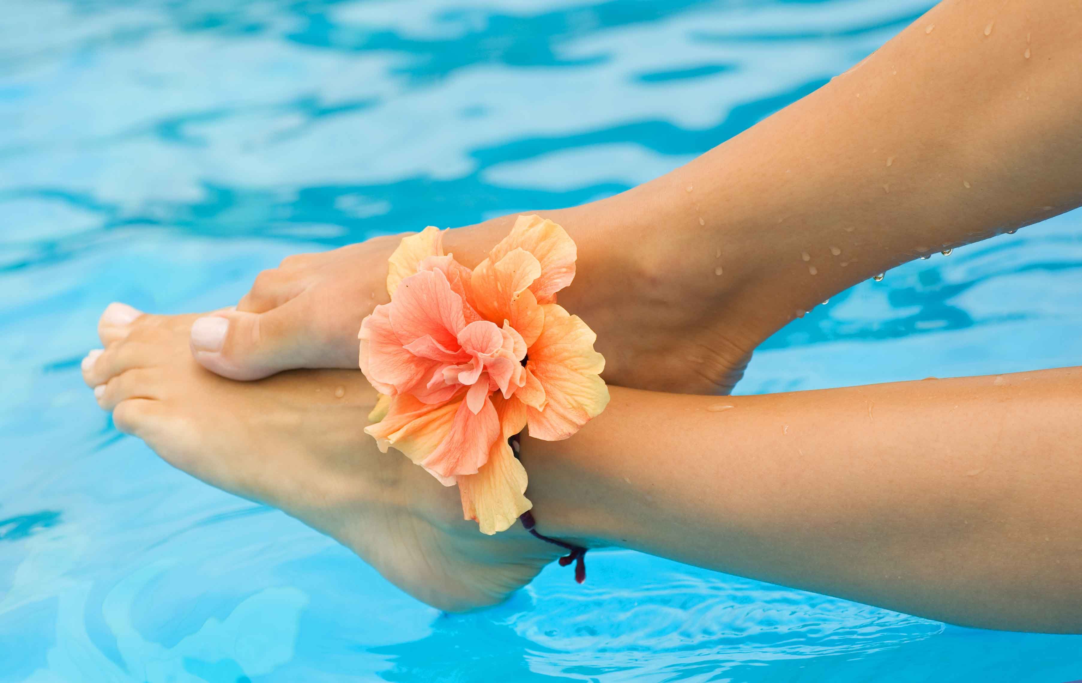 pies mojado en una piscina con una flor encima