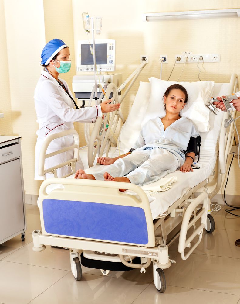 Mujer acostada en una cama de hospital junto a médicos