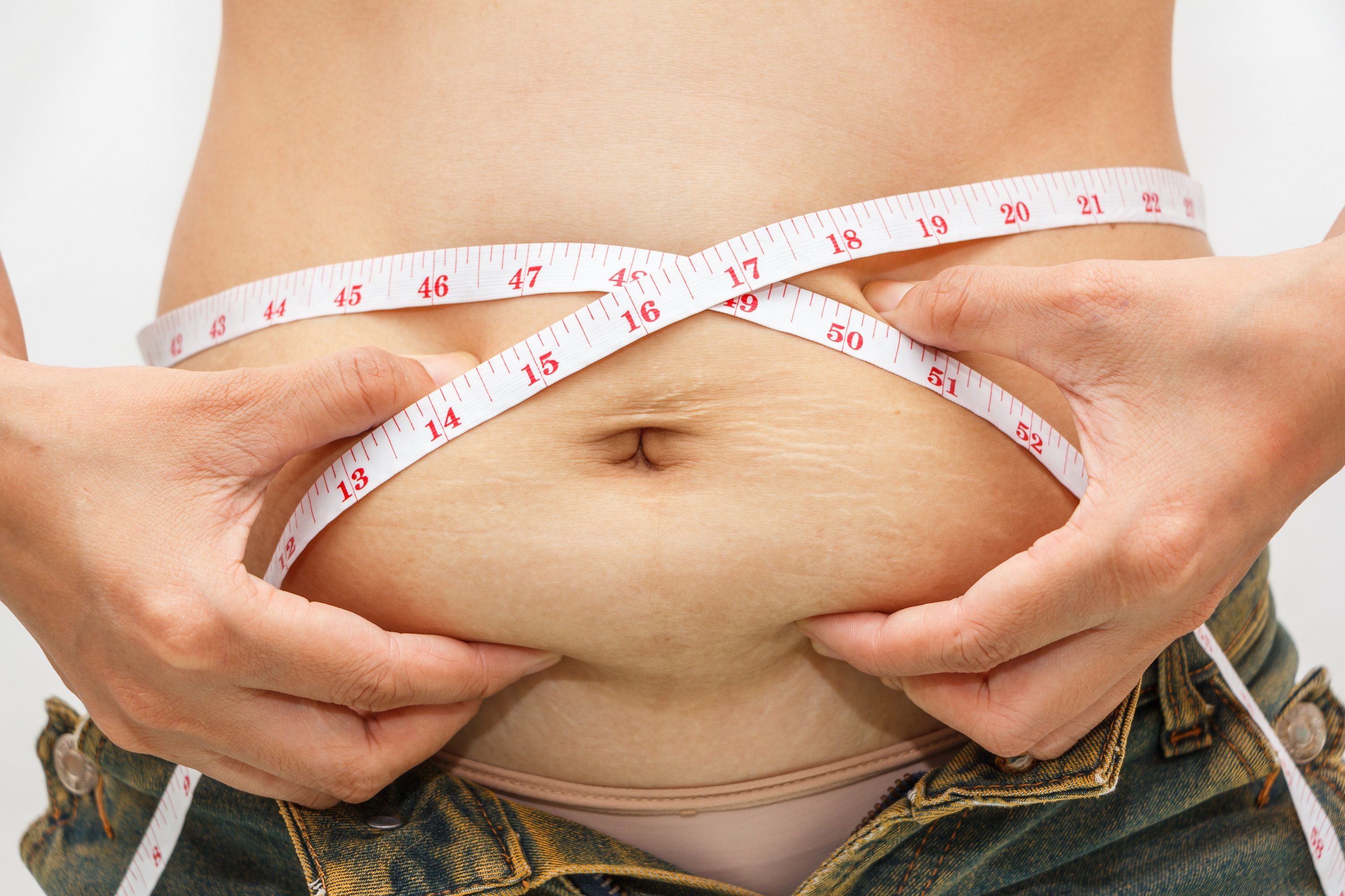 Mujer tocando grasa localizada en su abdomen