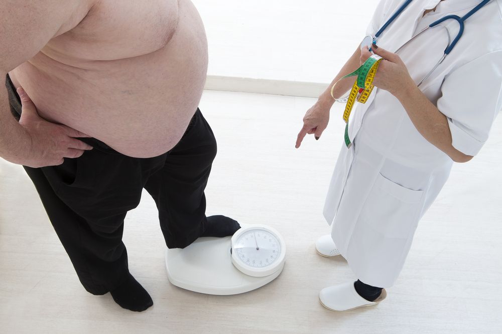hombre con obesidad pesándose en una vascula