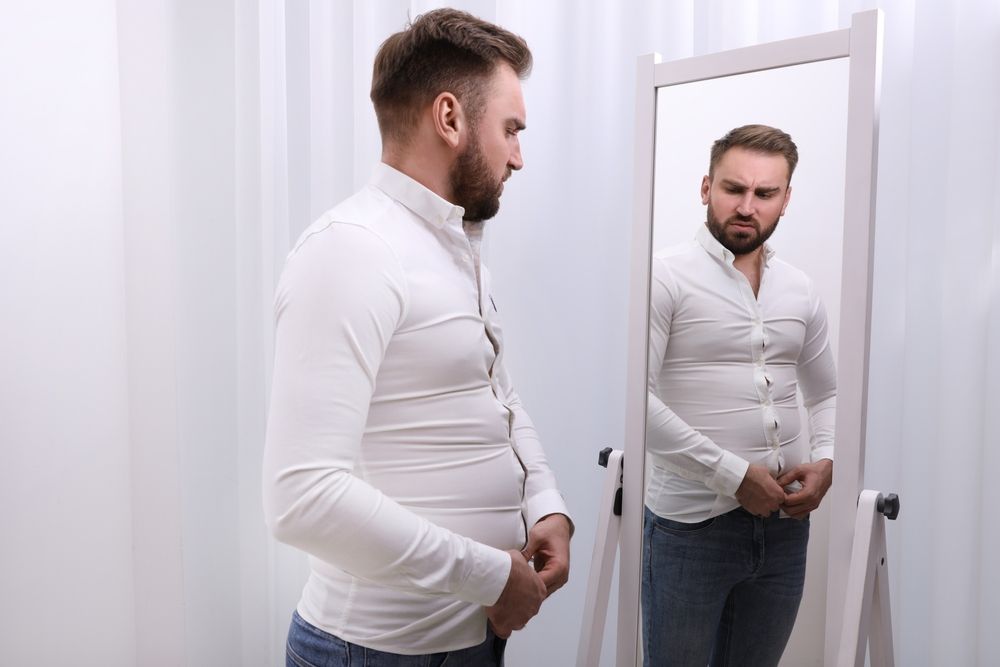 hombre con unos kilos de más midiendose una camisa