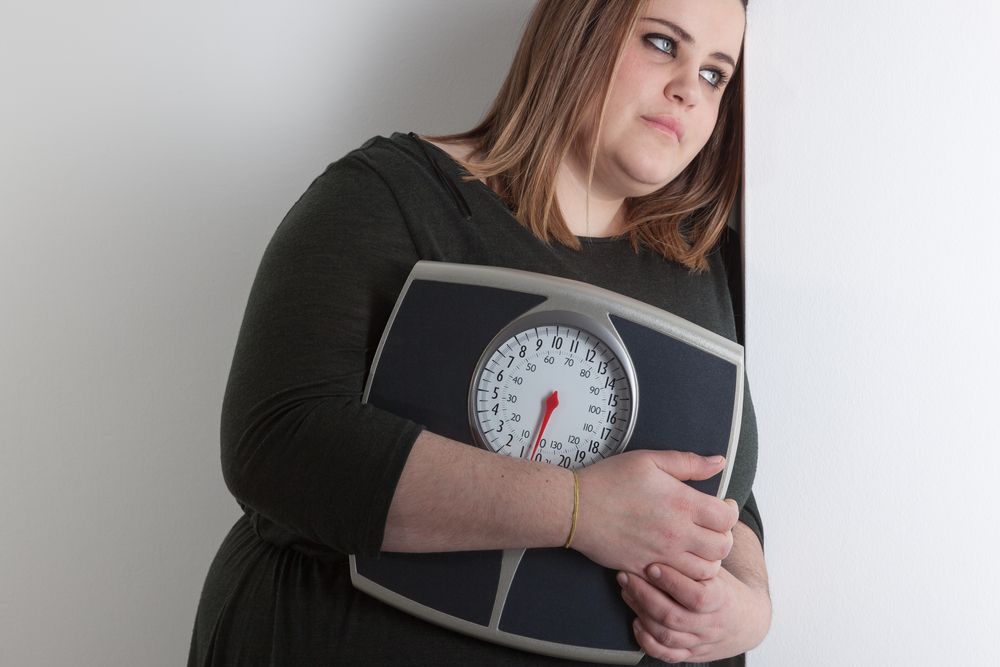 mujer con sobrepeso sosteniendo una báscula